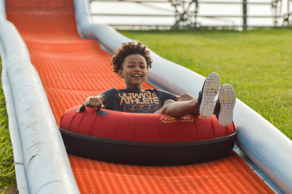 Child Having Fun Sliding Down The Tubing Hill