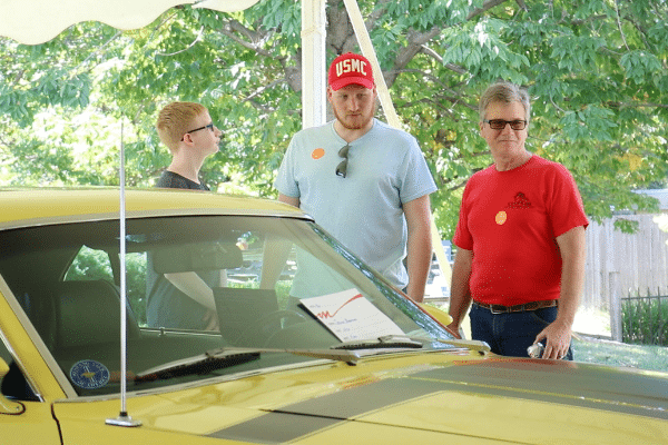 Three Men Looking At Yellow Vintage Car