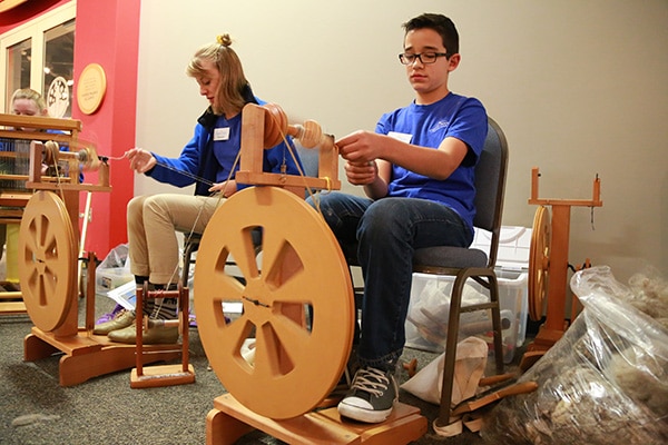 Image of a young boy spinning wool