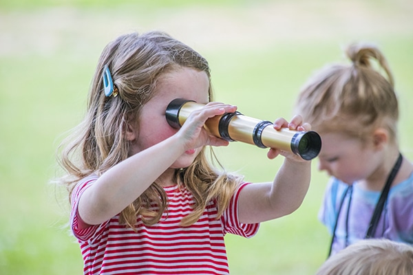child playing with telescope at playtime on the prairie