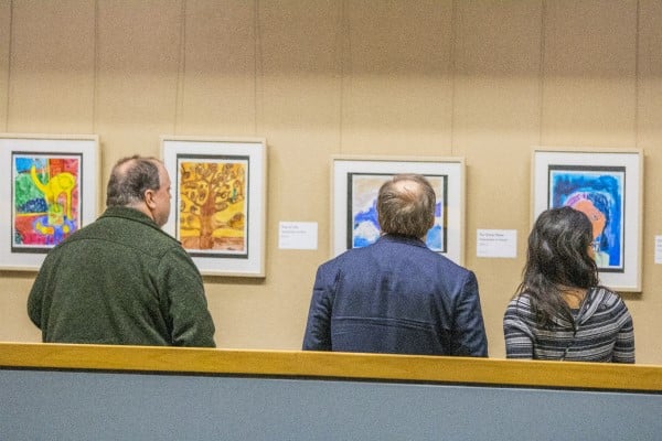Three people looking at artwork in the Welcome Center