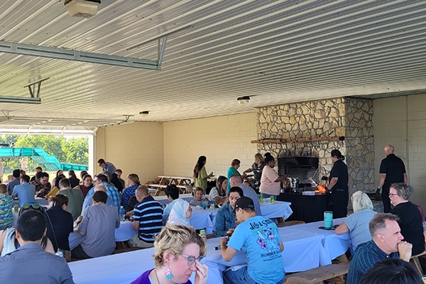 people eating at picnic tables inside a shelter
