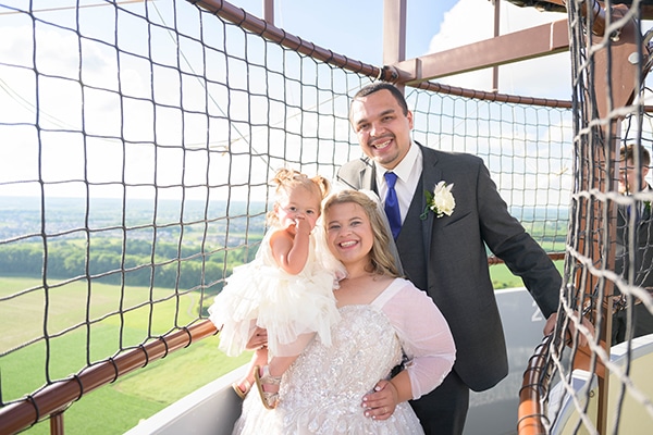 Bride and groom with flower girl in balloon gondola