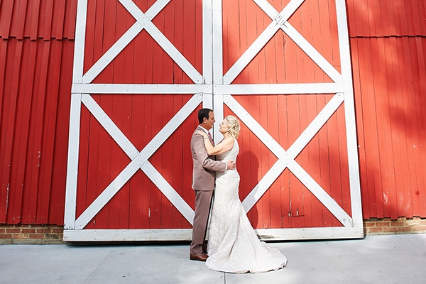 bride and groom standing in front of two red barn doors