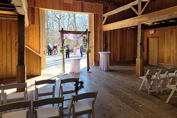 chairs and tables set up inside of a wooden building with people in the background