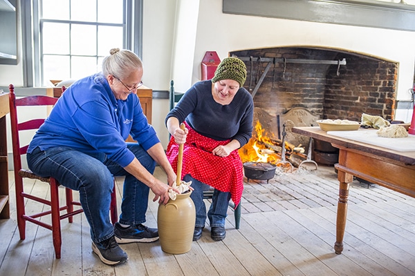 Two people churning butter in the William Conner House.
