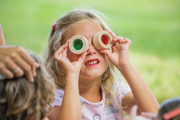 A child looking through two different colored lenses. 